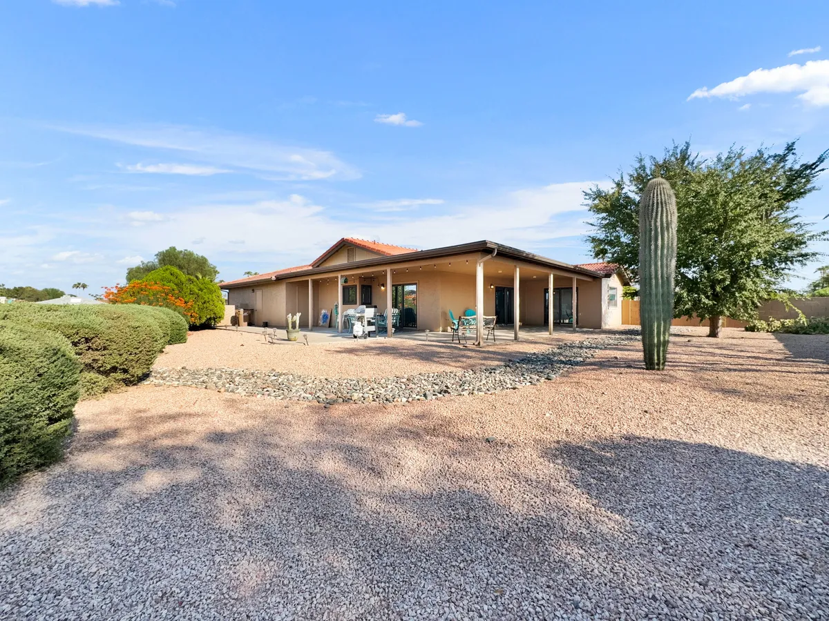 An inviting exterior shot showing the home's landscaped area, mature cactus, and a patio space perfect for outdoor relaxation and gatherings. The tranquil mood and visible connection to nature highlight the appeal of stepping outside for fresh air and recreation.