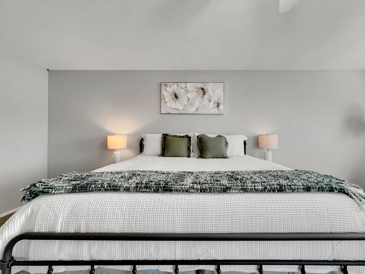 A second inviting bedroom, styled with a comfortable bed, soft bedding, wall art, and bedside lamps. The room is bathed in natural light, creating a peaceful and welcoming space ideal for relaxation or reading.