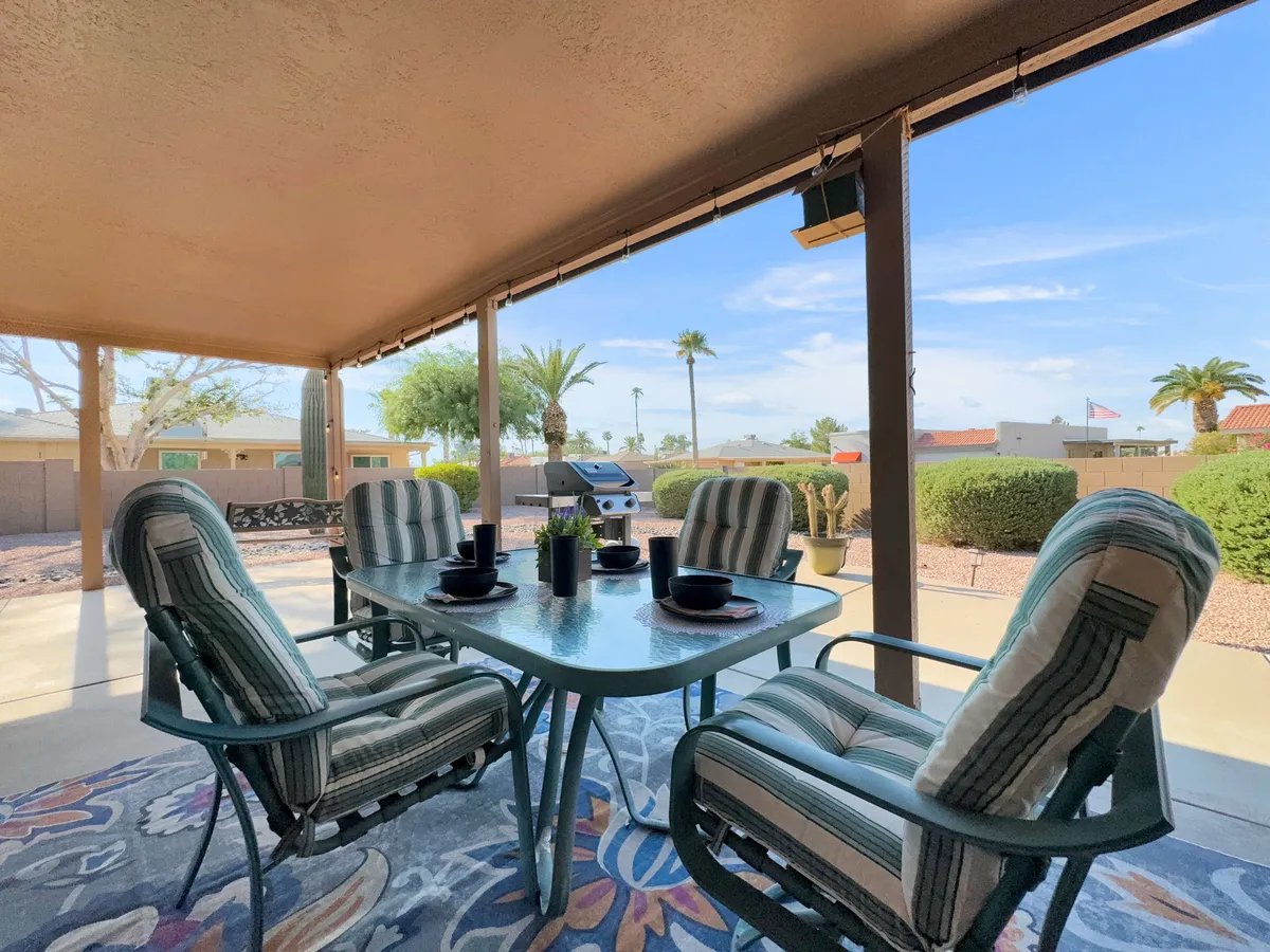 This image shows a welcoming backyard patio setup with a dining table and chairs, a grill ready for barbecuing, and lush potted plants creating a private, relaxed atmosphere. The space is ideal for alfresco dining or social gatherings, with the layout positioned to maximize comfort and enjoyment of the Arizona outdoors.