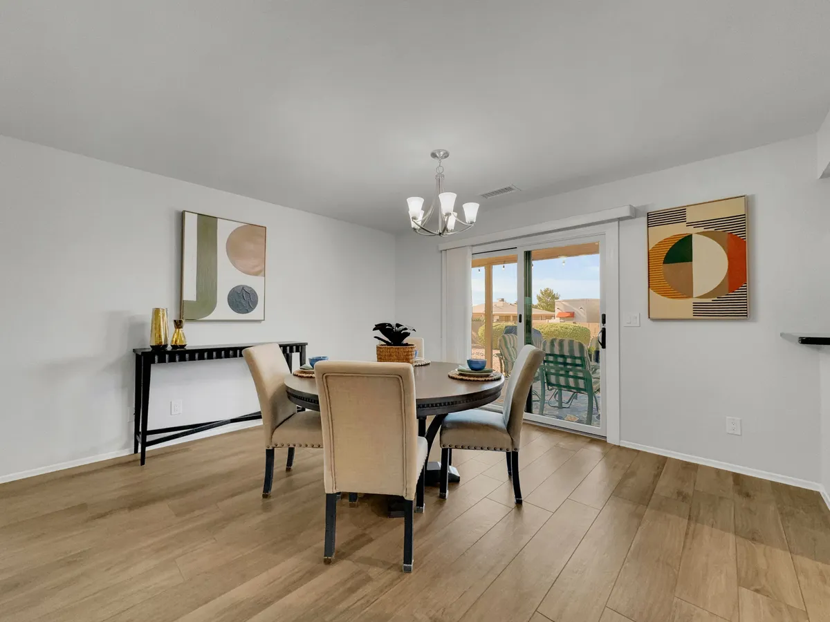 A formal dining room with a beautifully set dining table beneath an elegant chandelier, complemented by sophisticated artwork on the walls. The space feels welcoming and is designed for memorable meals and lively conversation.